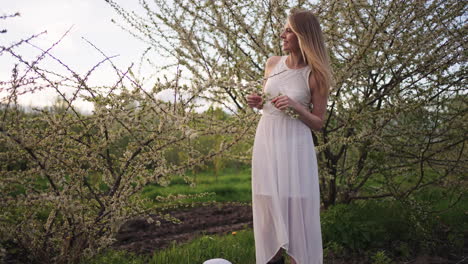 tender-lady-in-white-dress-is-standing-in-blooming-garden-in-spring-day-beauty-of-woman-and-nature